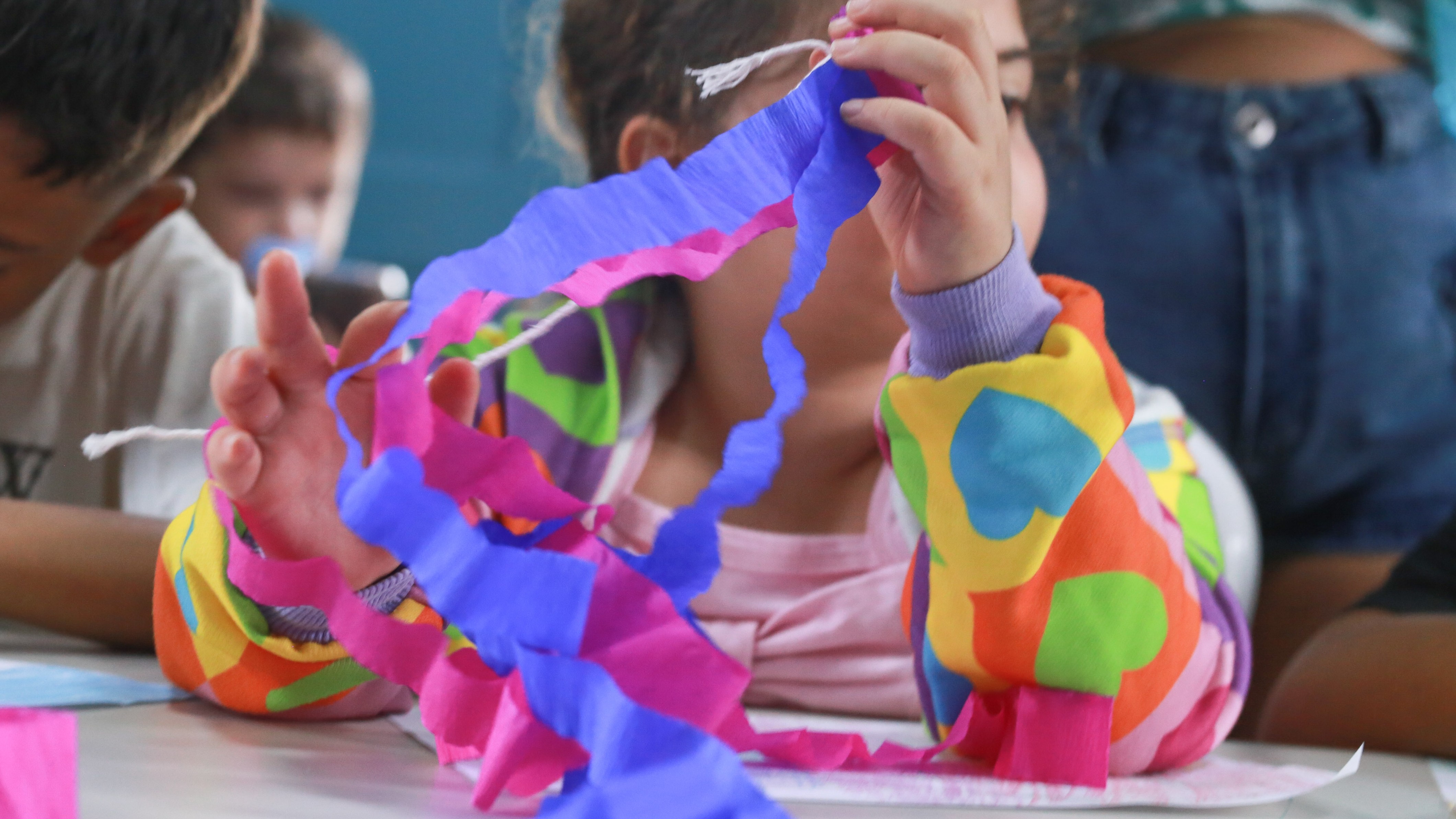 uma criança brincando com tiras de papel coloridas